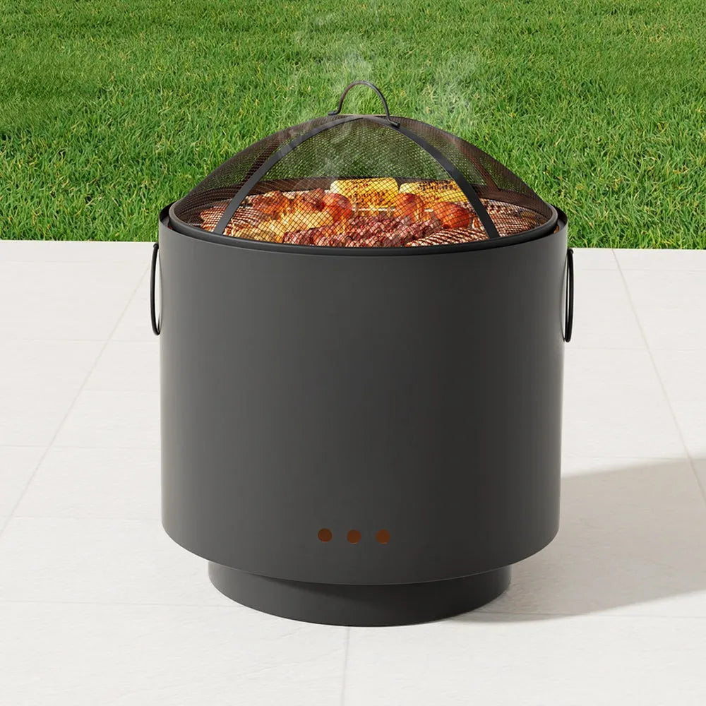 Black cylindrical fire pit with grill grate on a grassy background